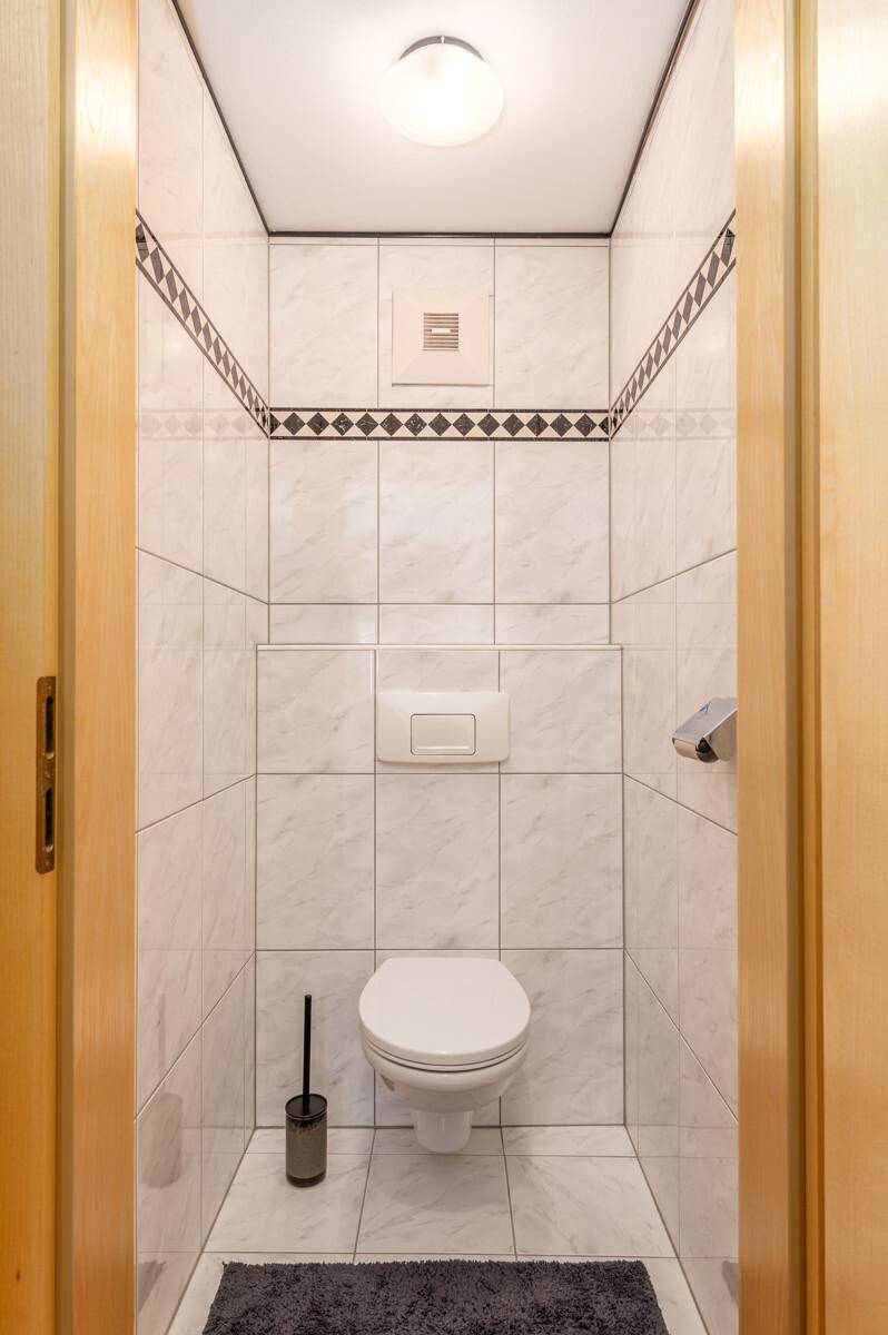 Kleines WC mit wandhängender Toilette und weißen Fliesen.