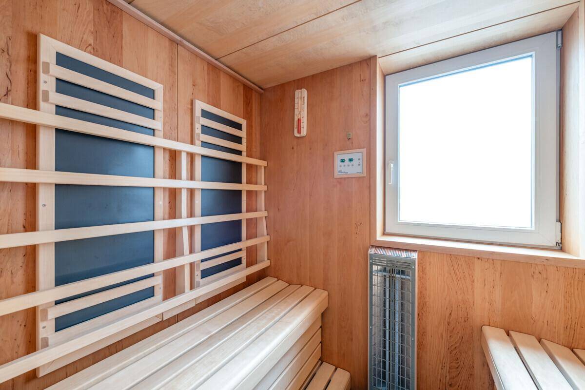 Gemütliche Holzsauna mit Sitzbänken und einem Fenster für natürliche Belüftung.