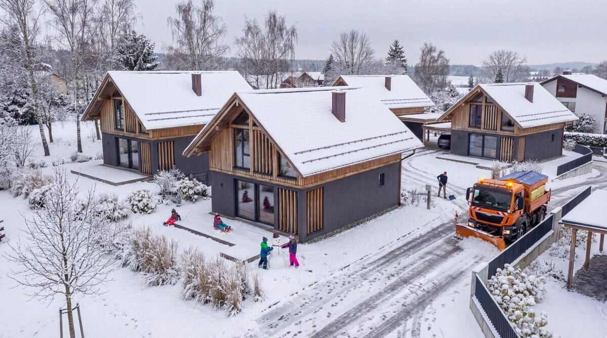 Winterliche Luftaufnahme der modernen Häuser mit verschneiten Dächern und spielenden Kindern.