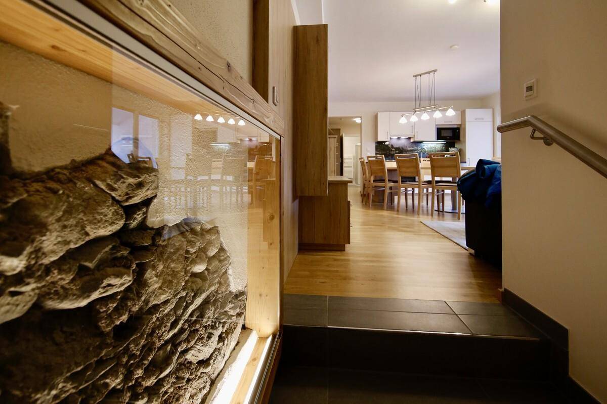 Eingangsbereich mit dekorativer Steinwand und Blick in den offenen Wohn-Essbereich mit Holzboden.