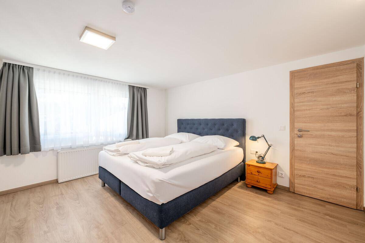 Helles Schlafzimmer mit großem Doppelbett, Holzboden und Holztür.