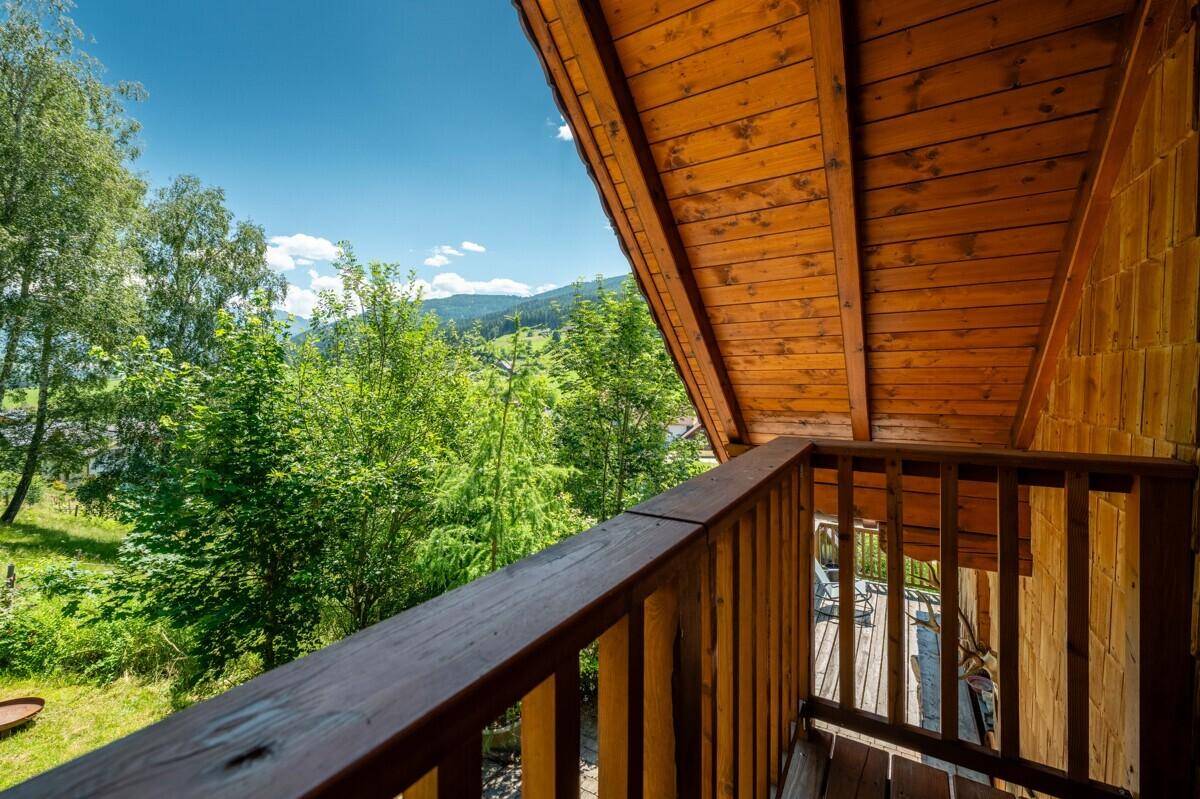 Geräumiger Holzbalkon mit schöner Aussicht auf die umliegende grüne Landschaft und Berge.