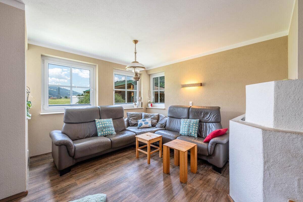 Gemütliches Wohnzimmer mit bequemen Ledersofas, Holzboden und Blick auf die umliegende Landschaft.