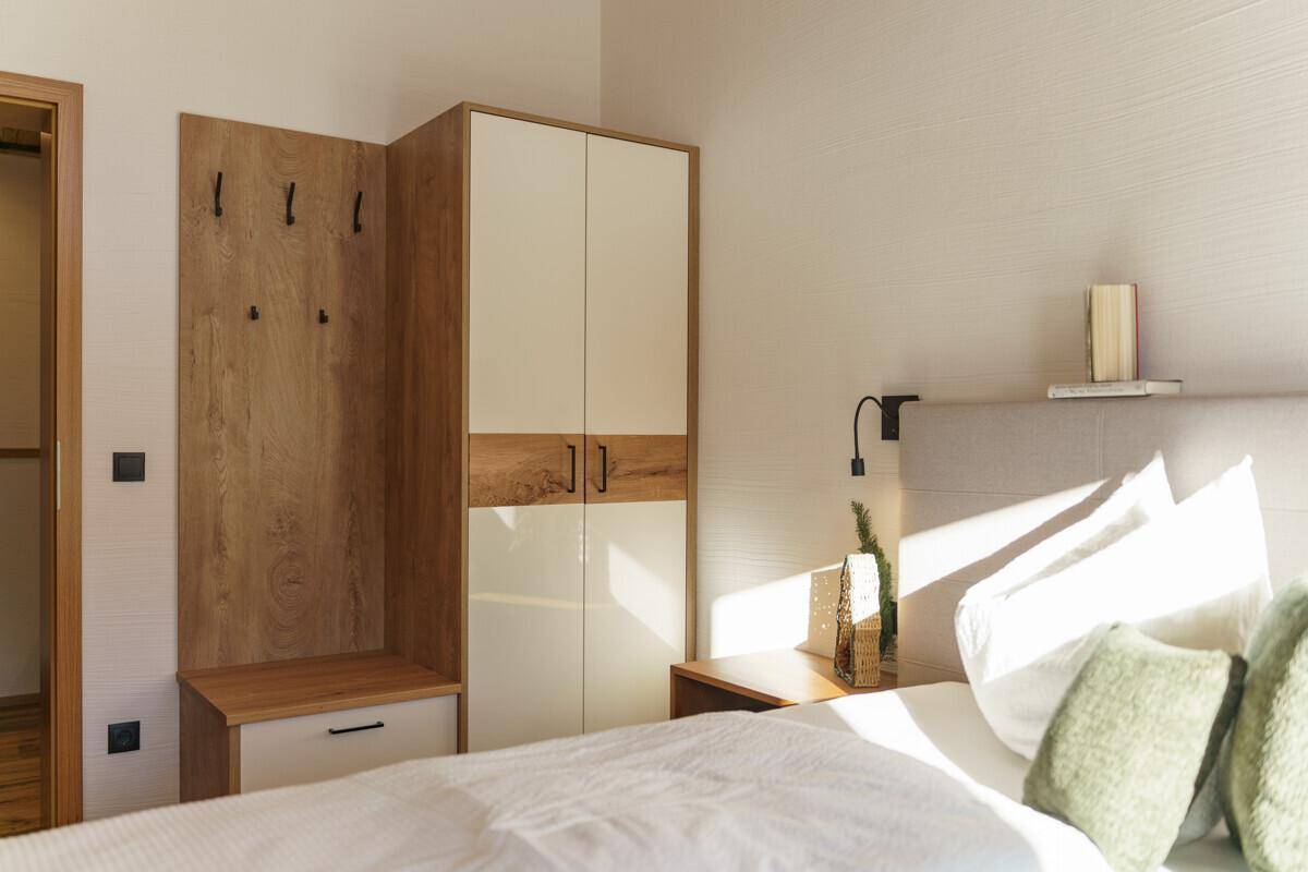 Modern eingerichtetes Schlafzimmer mit Doppelbett, Einbauschrank und schwebendem Nachttisch.