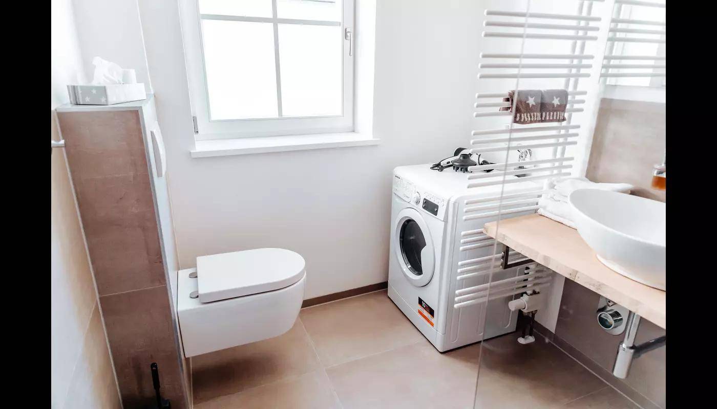 Helles Badezimmer mit Waschmaschine, Heizkörper und modernem Waschbecken.