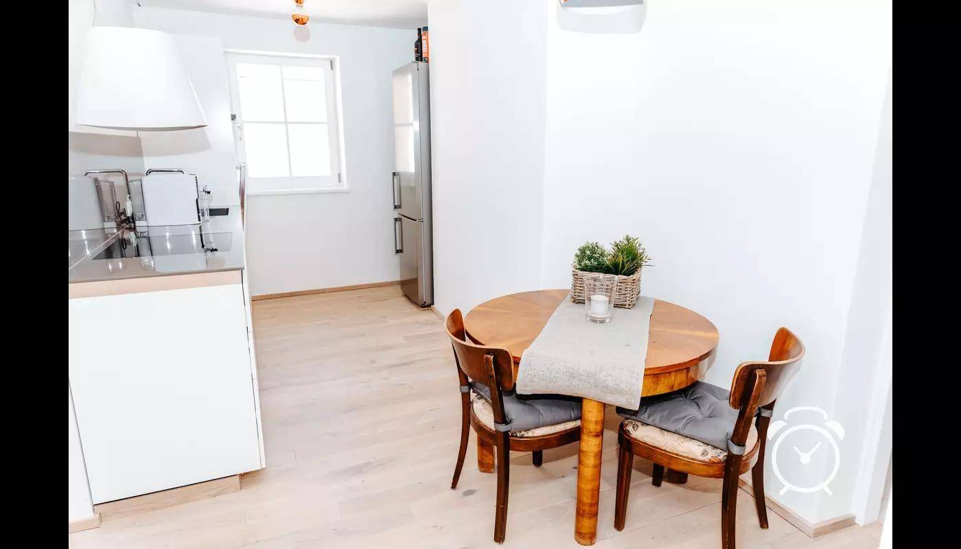 Essbereich in der Küche mit rundem Holztisch und modernen Küchenschränken.