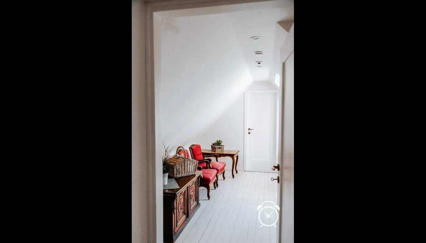 Gemütlicher Dachbodenbereich mit zwei roten Sesseln und antikem Holzschrank.