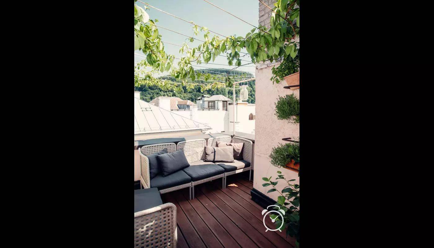 Gemütliche Dachterrasse mit Sitzmöbeln und Blick auf die grüne Umgebung.