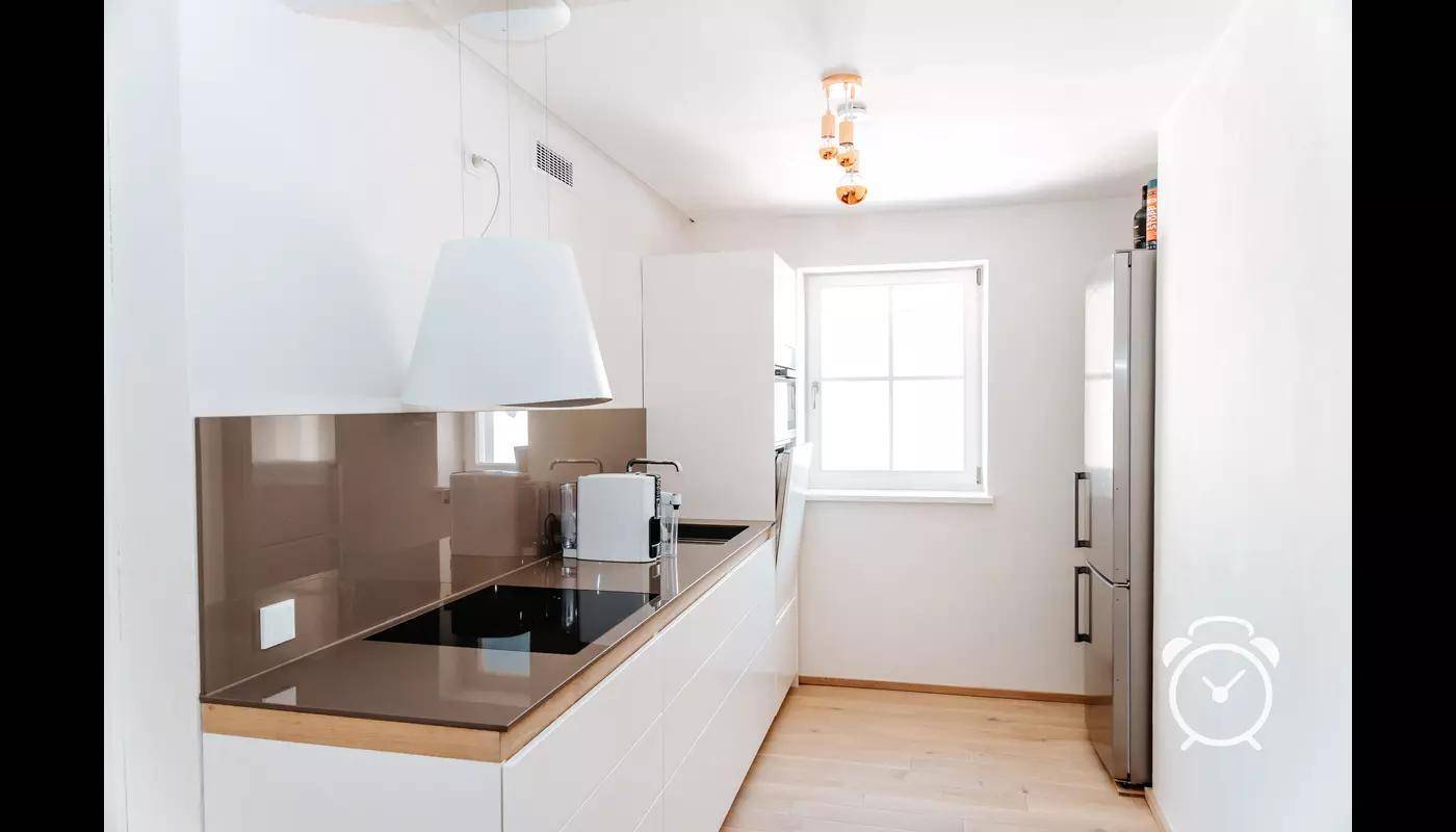 Helle, moderne Küche mit weißen Schränken, Induktionskochfeld und Fenster.