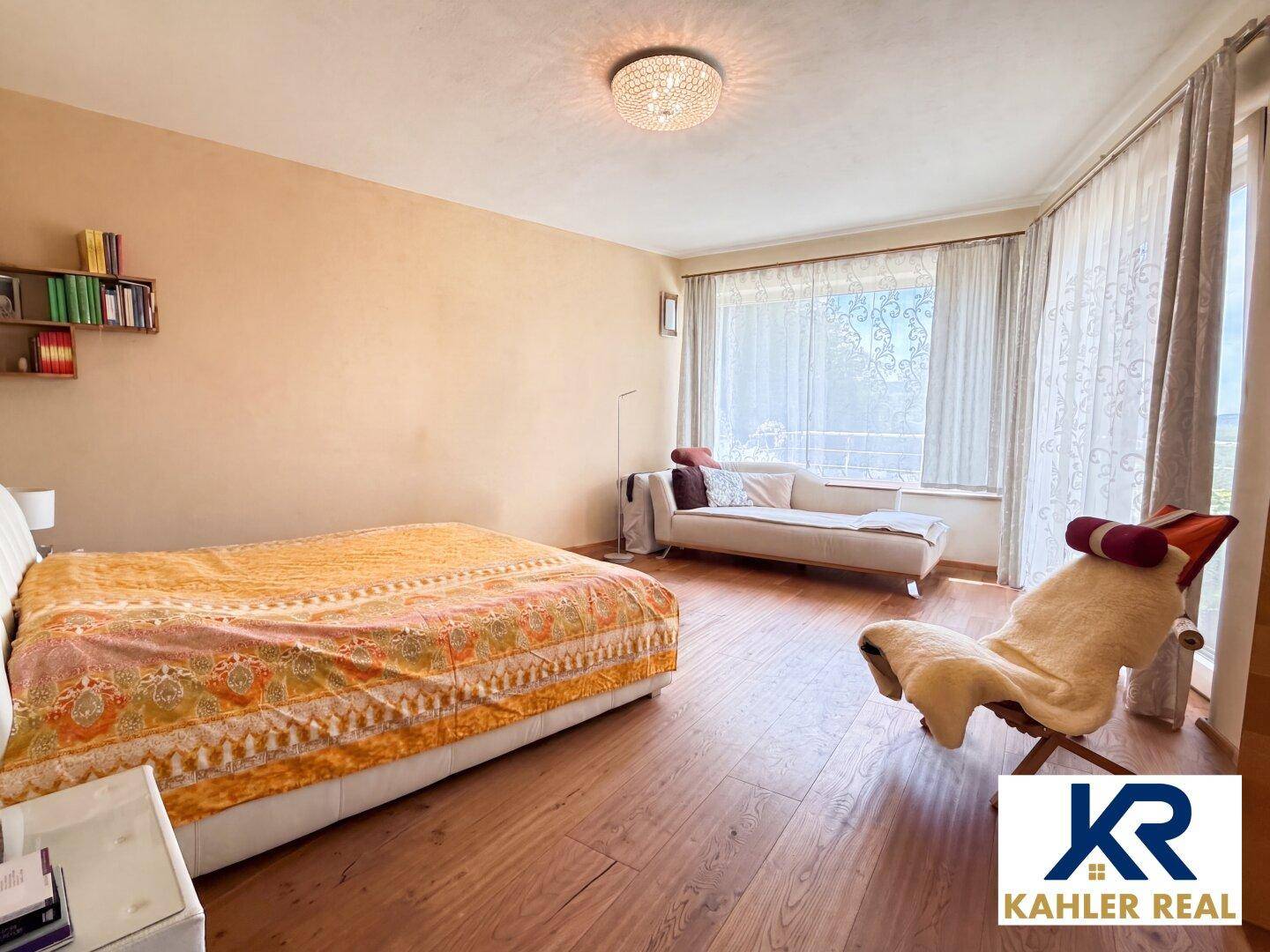 Geräumiges Schlafzimmer mit Holzboden, großem Fenster und gemütlicher Liegefläche.