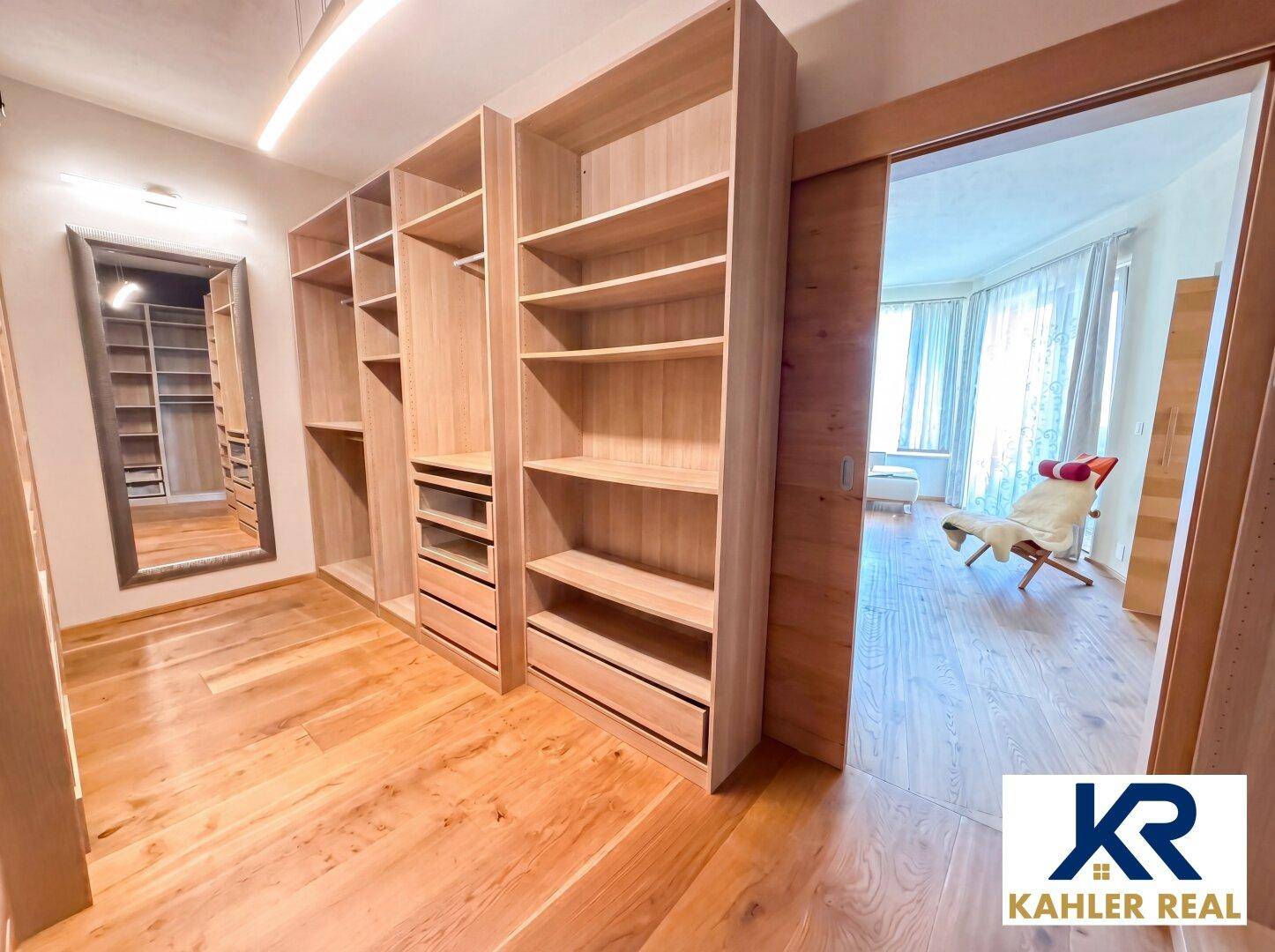 Begehbarer Kleiderschrank mit maßgefertigten Holzregalen und viel Stauraum.