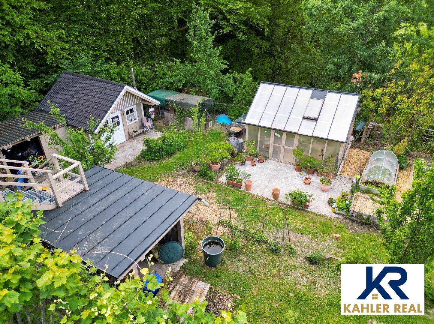 Weitläufiger Gartenbereich mit Gewächshaus, Gartenhaus und verschiedenen Anbauflächen.