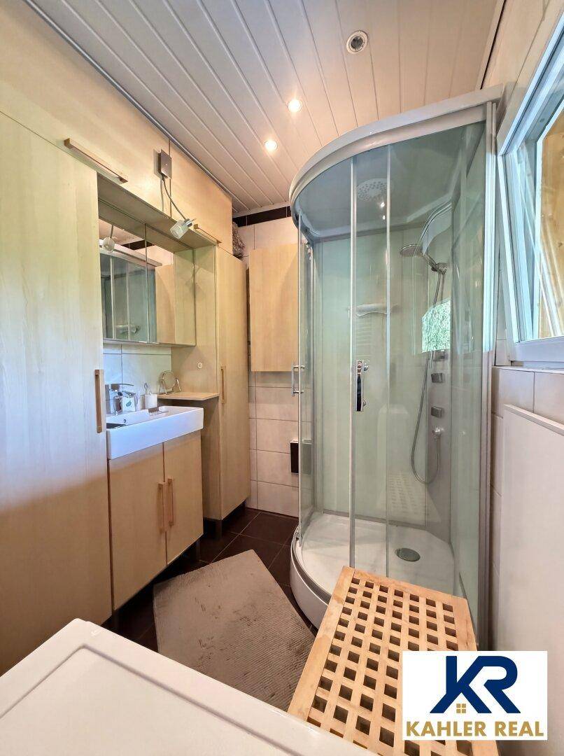 Badezimmer mit Duschkabine, Waschbecken und Spiegelschrank, funktional eingerichtet.