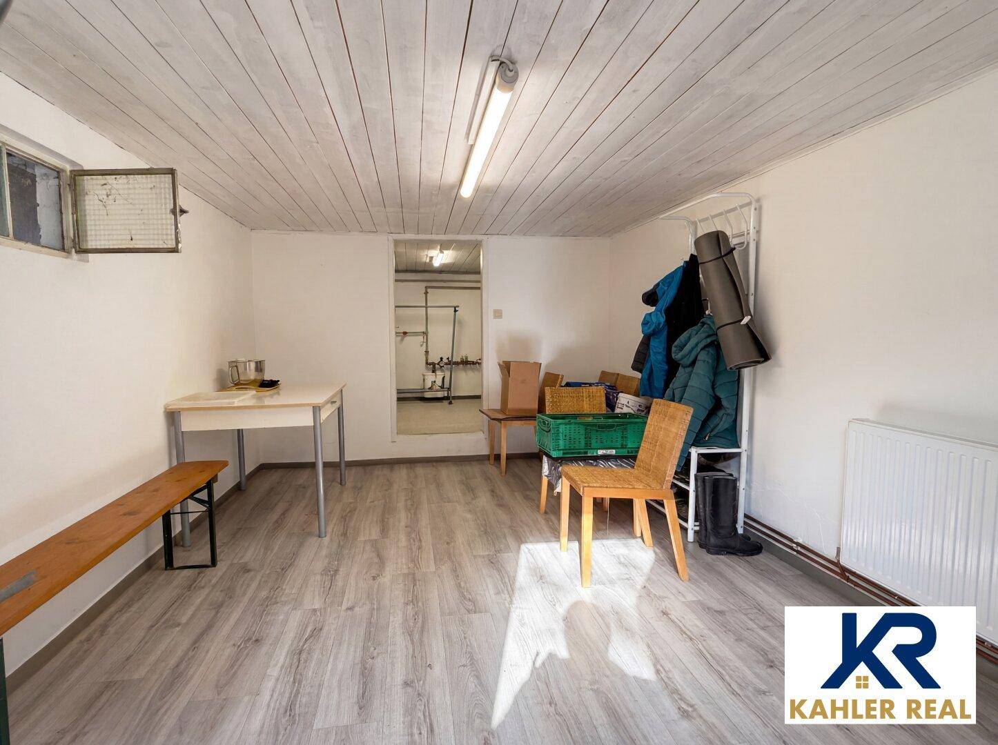 Geräumiger Kellerraum mit Laminatboden, Heizkörper und Stauraum für verschiedene Gegenstände.