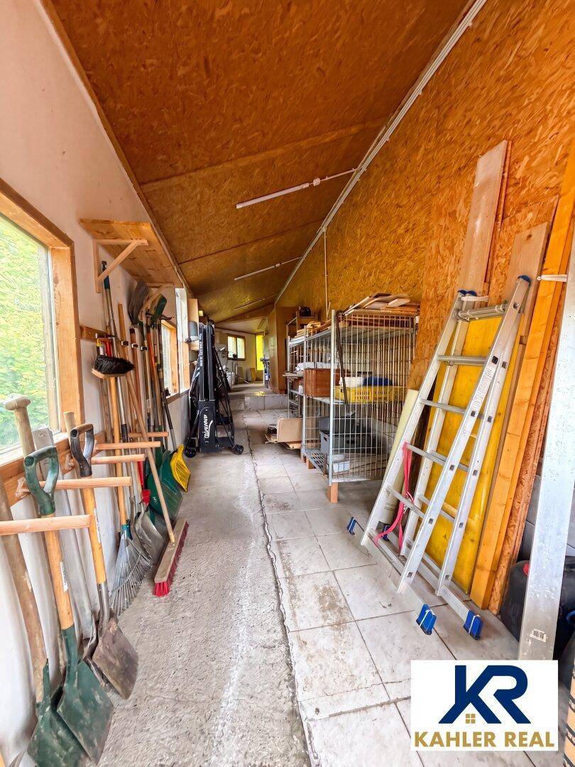 Langer Abstellraum mit Werkzeugen, Leitern und Regalen, ideal für Lagerung und Hobby.
