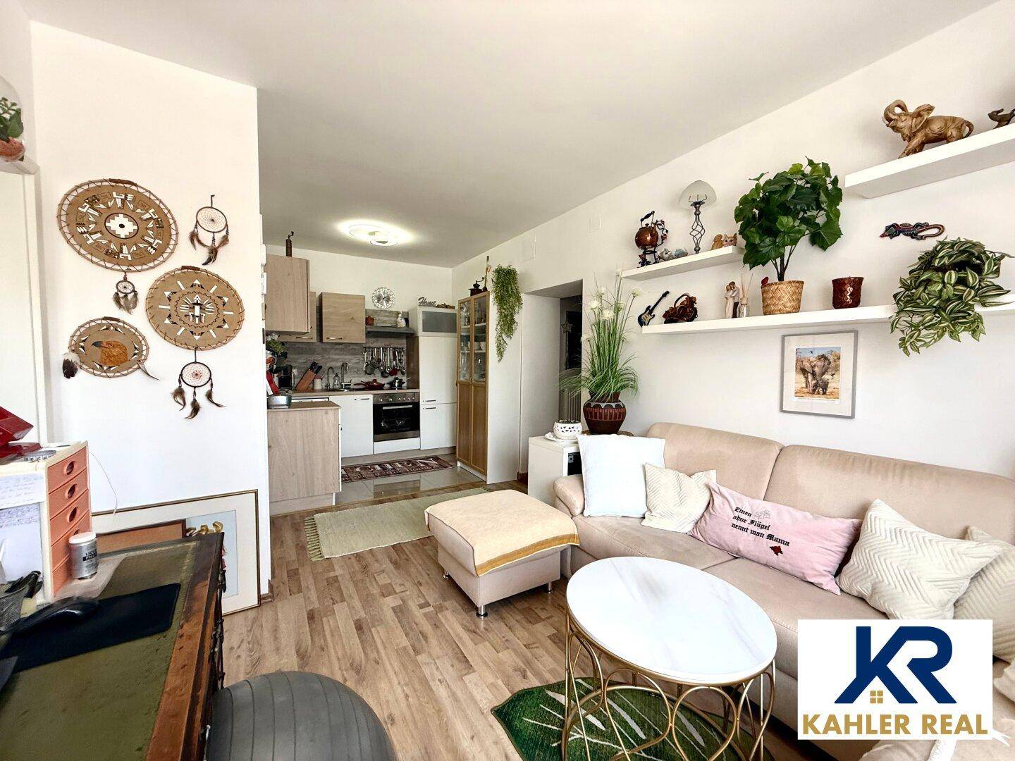 Gemütlicher Wohnbereich mit Sofa, Couchtisch und offener Verbindung zu einer kleinen Küchenzeile.