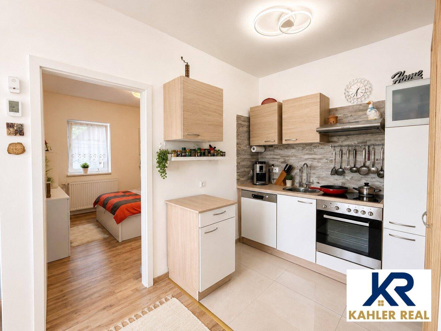 Moderne Küche mit hellen Holzfronten, integrierten Geräten und direktem Zugang zum Schlafzimmer.