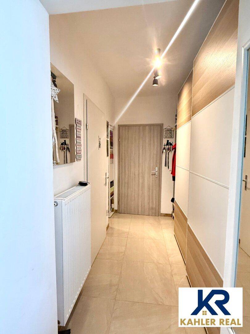 Heller Flur mit Fliesenboden, Einbauschränken und Zugang zu den verschiedenen Räumen der Wohnung.