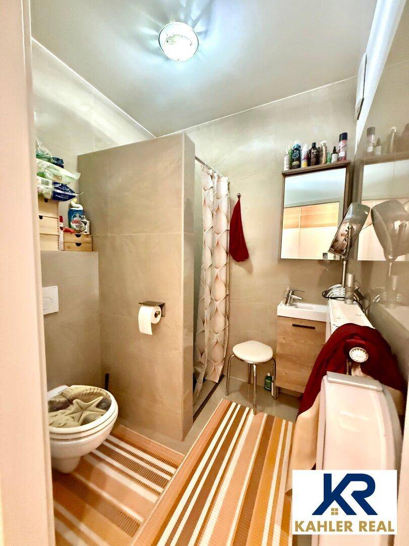 Modernes Badezimmer mit Dusche, WC, Waschbecken und gestreiften Teppichen für mehr Komfort.