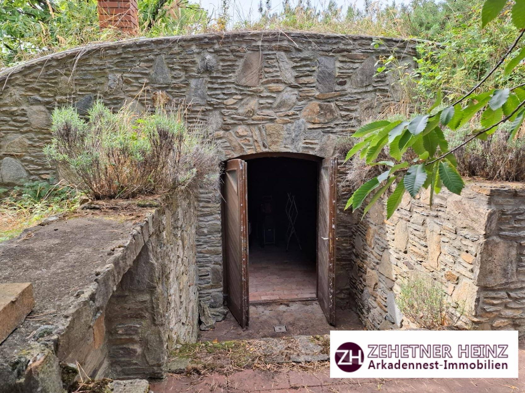 Eingang zu einem traditionellen Erdkeller mit Holztür und Steinmauern.
