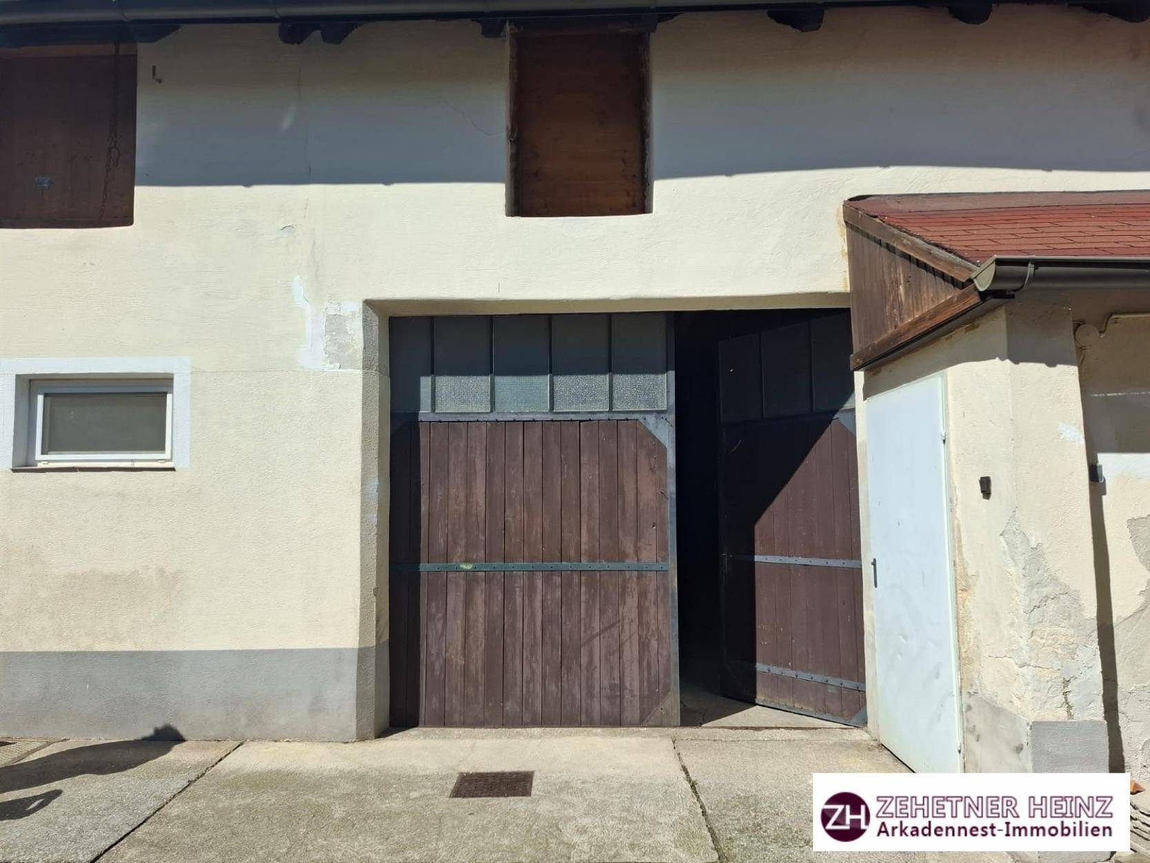 Alte Scheunentore aus Holz an einer verputzten Fassade eines ländlichen Gebäudes.