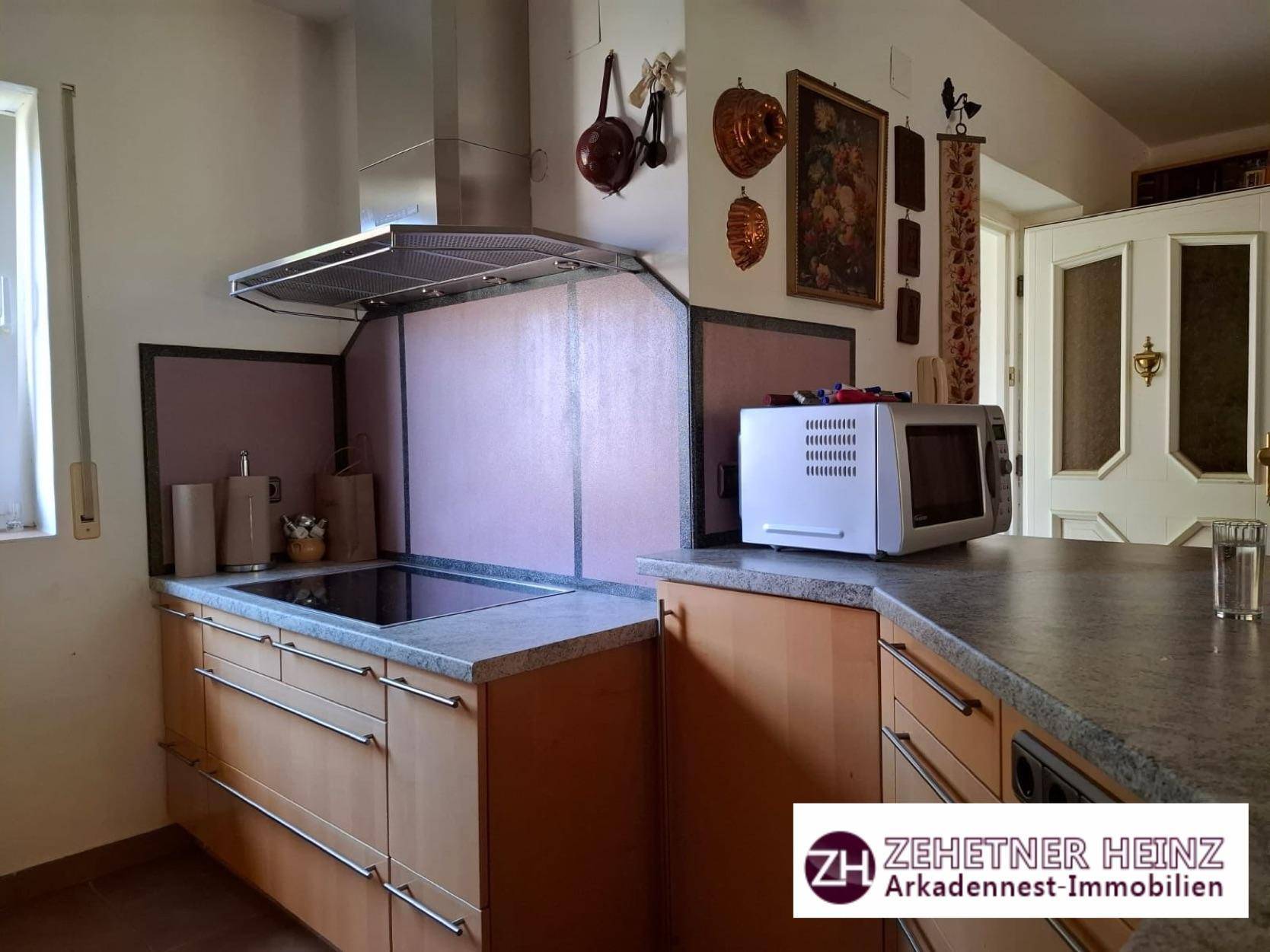 Küche mit Holzschränken, Granitarbeitsplatte und Dunstabzugshaube über dem Kochfeld.