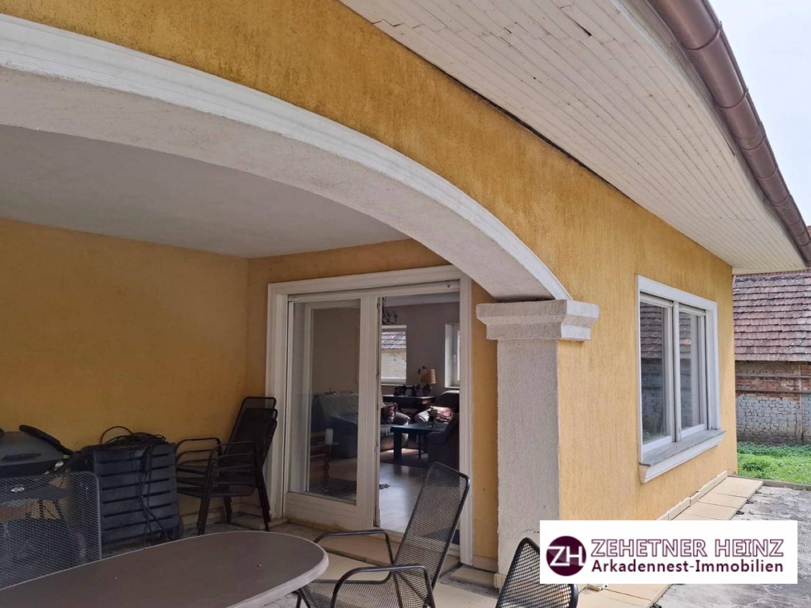 Überdachte Terrasse mit Zugang zum Innenbereich und Blick auf den Garten.