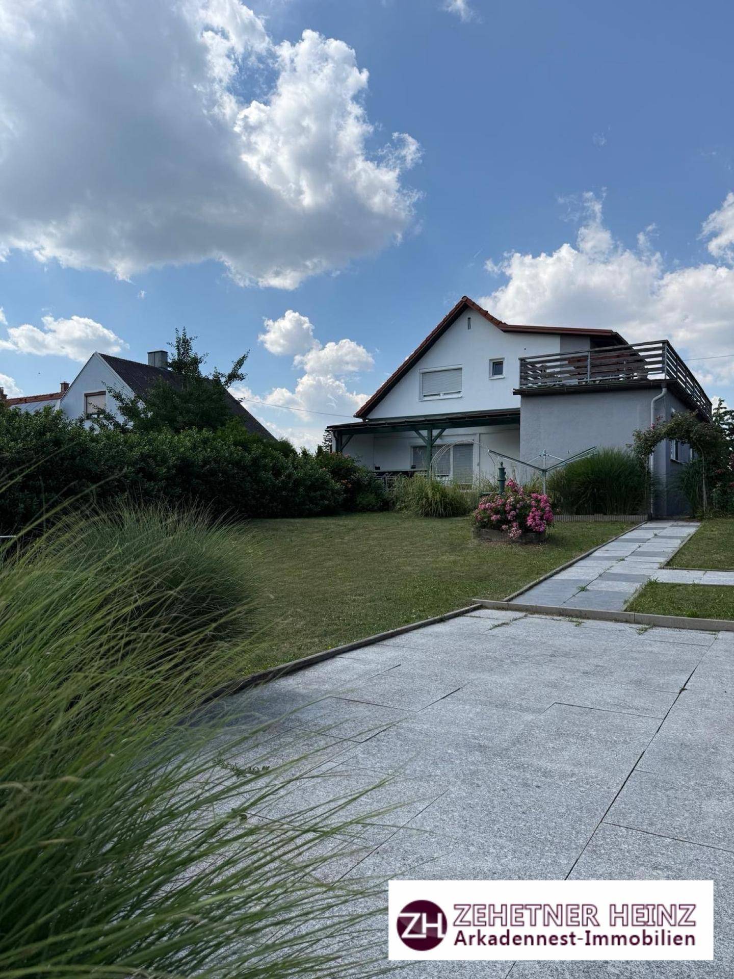 Gepflasterter Vorplatz mit Blick auf das Haus und den weitläufigen Gartenbereich.