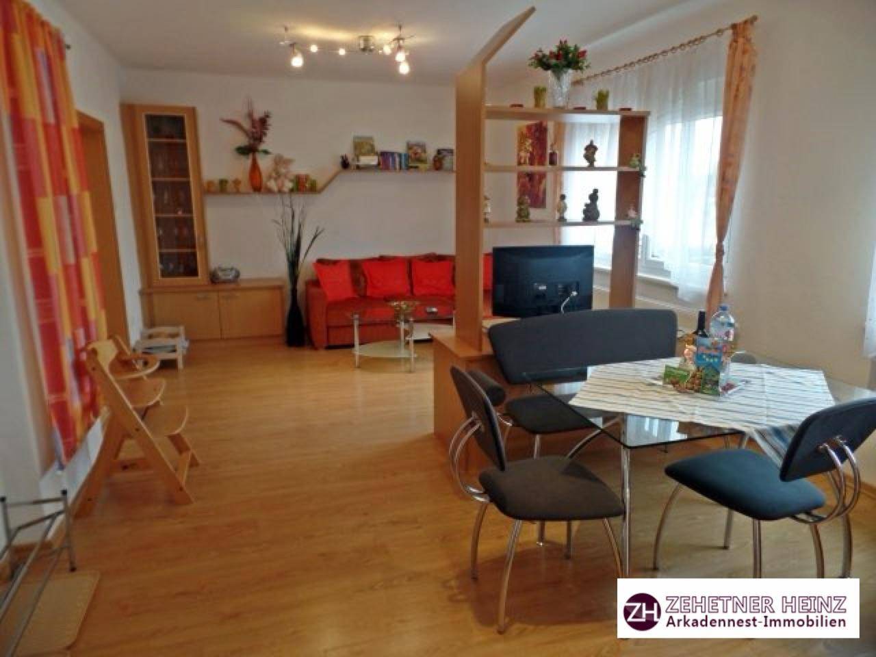 Heller Wohn-Essbereich mit Holzfußboden, Esstisch und gemütlicher Sofaecke.