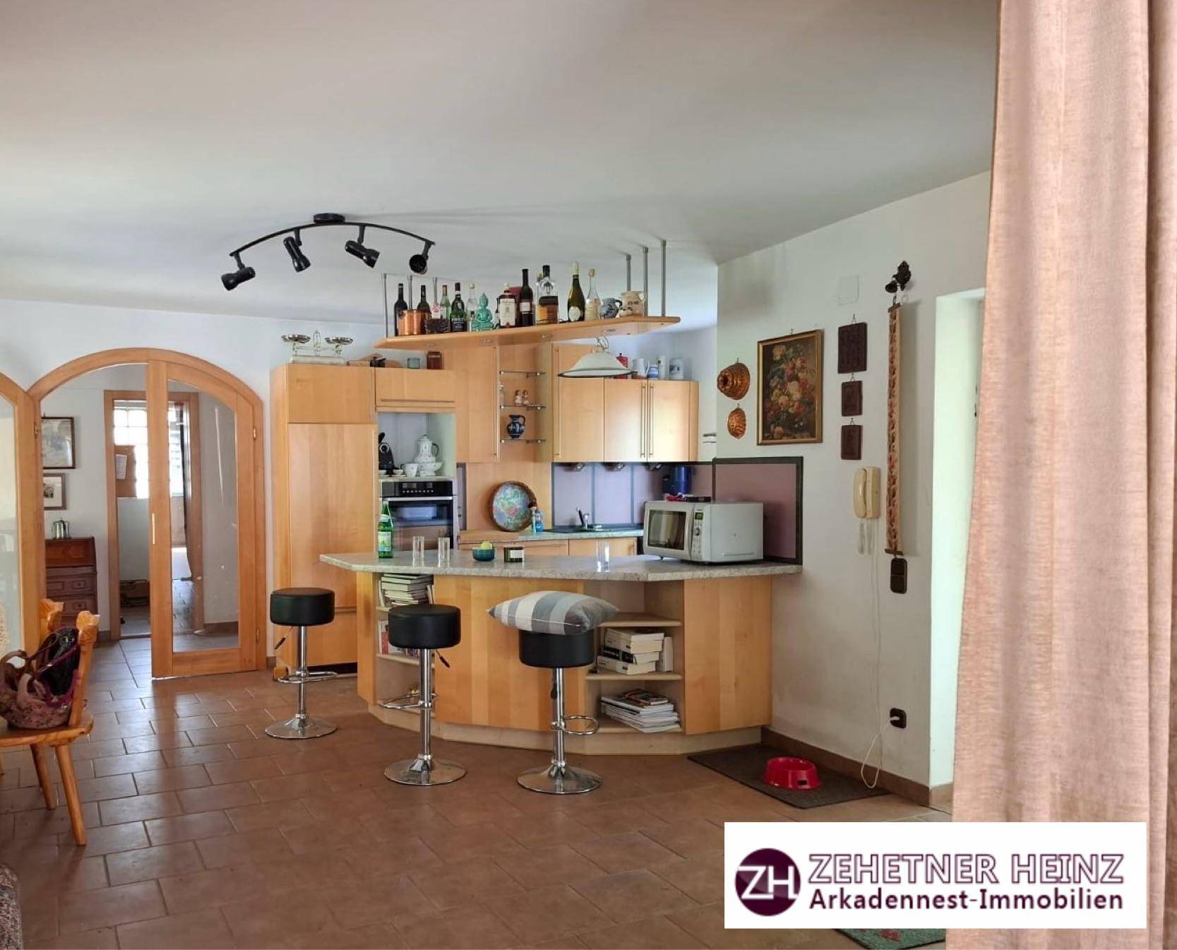 Offene Küche mit Frühstücksbar, Holzschränken und Terrakottafliesen.