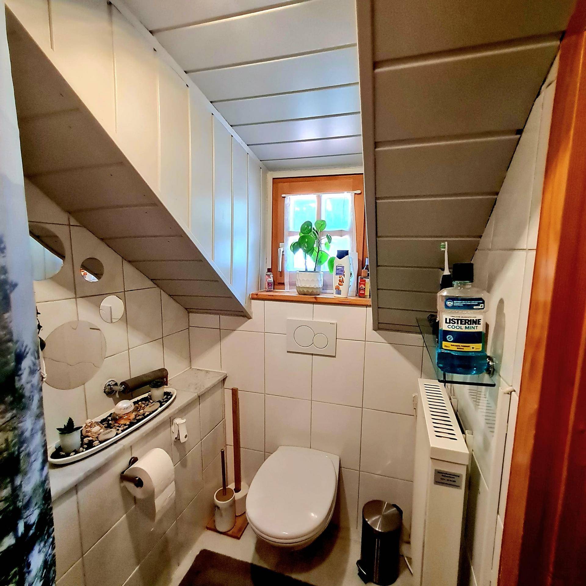 Kleines WC mit Toilette, Waschbecken und einem Fenster für Tageslicht.