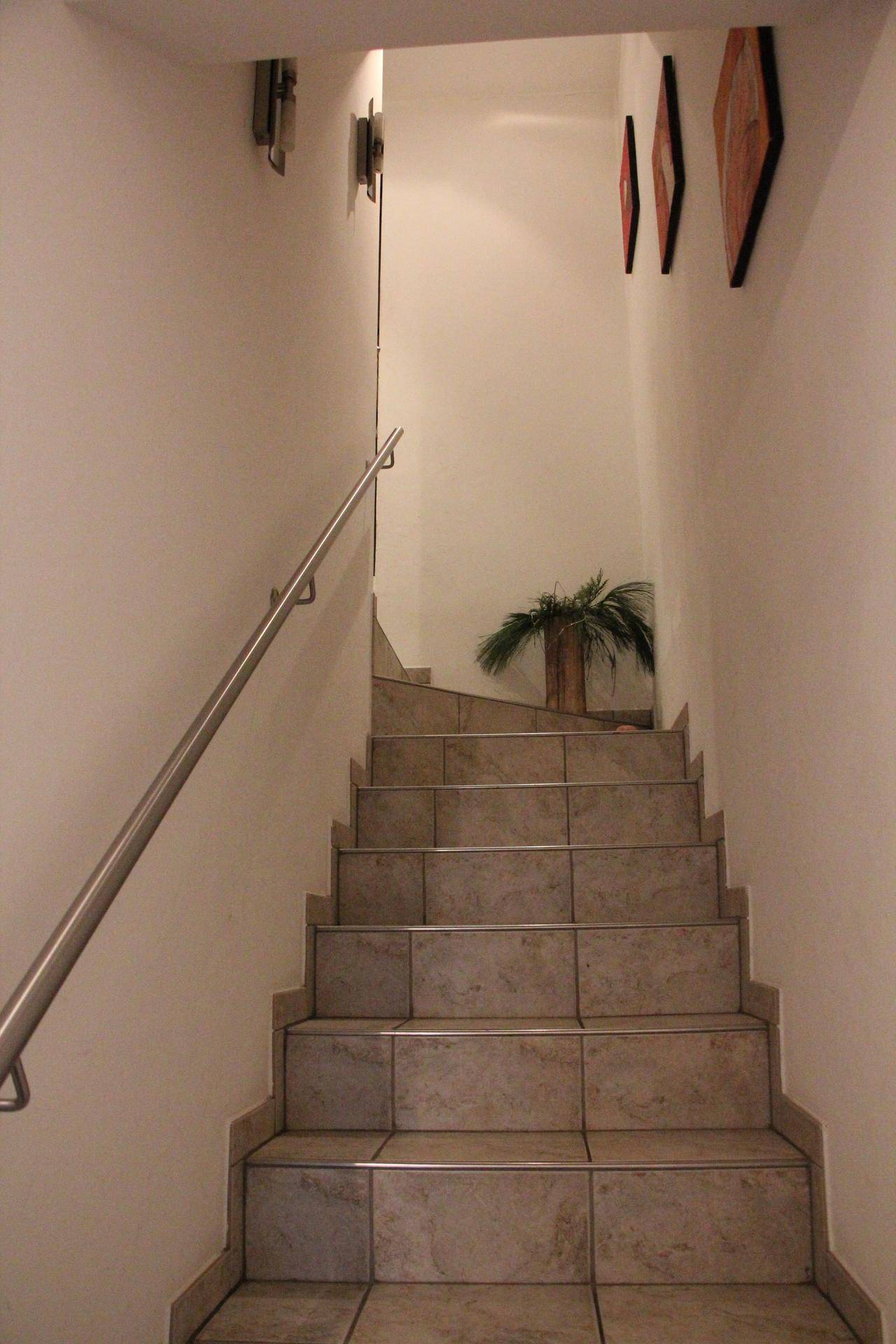 Heller Treppenaufgang mit beigefarbenen Fliesenstufen und modernem Metallgeländer, führt in die obere Etage.