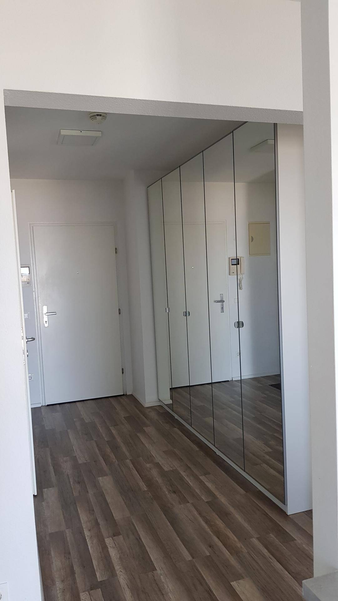 Heller Flur mit integrierten Spiegelschränken und modernem Laminatboden.