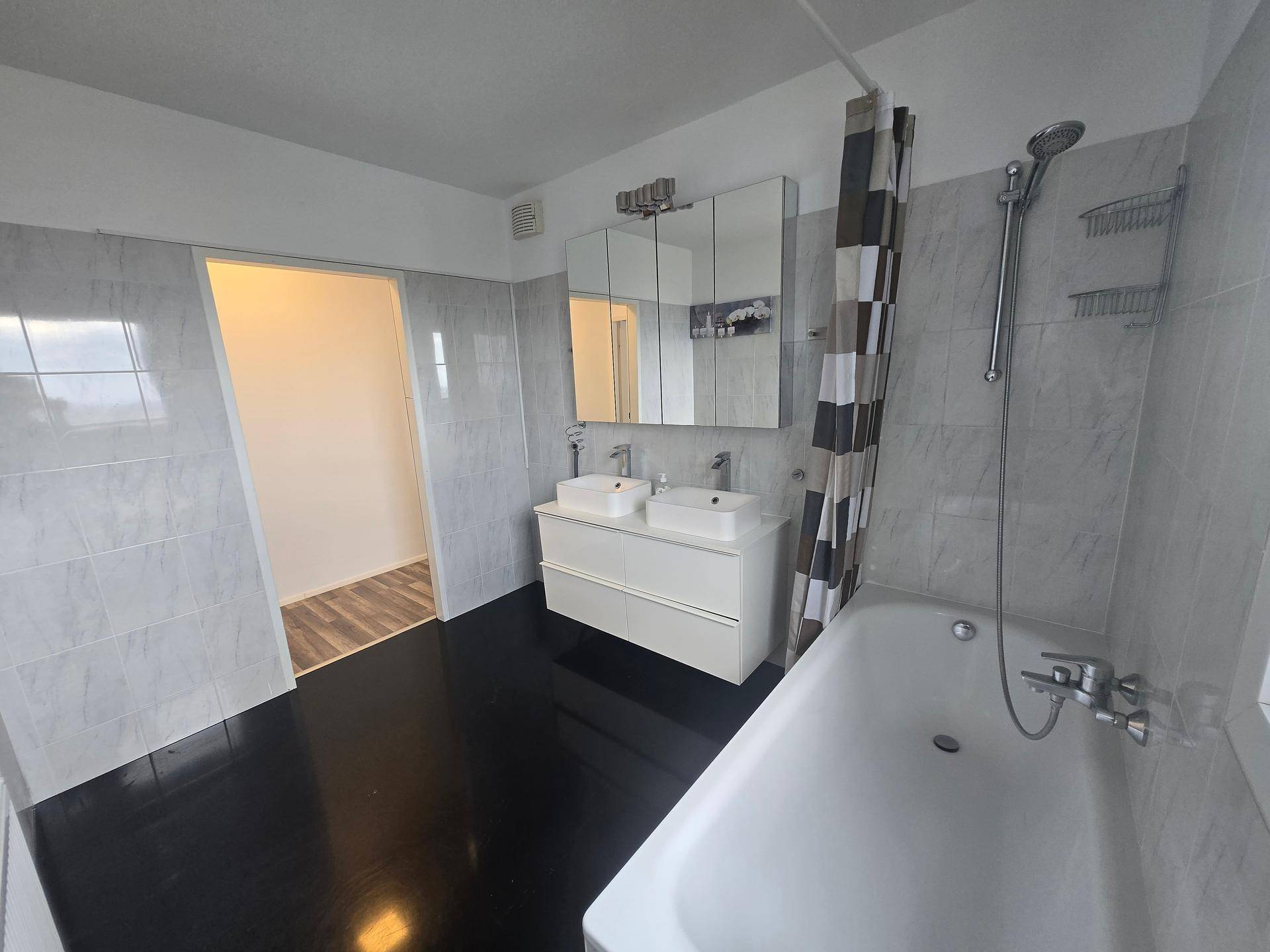 Modernes Badezimmer mit Badewanne, Doppelwaschbecken und hellen Fliesenwänden.