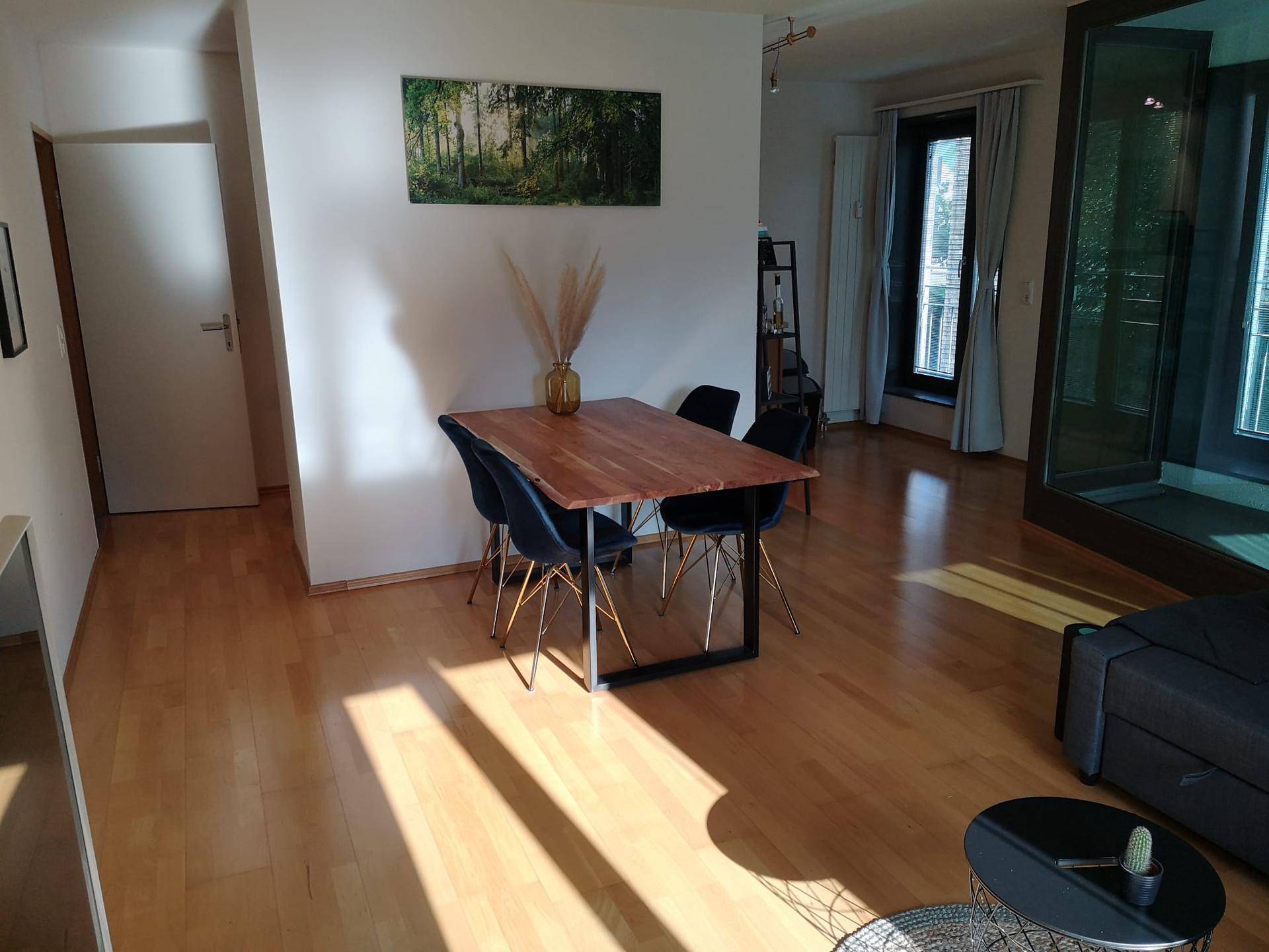 Offener Essbereich mit Holztisch und modernen Stühlen, verbunden mit dem Wohnbereich.