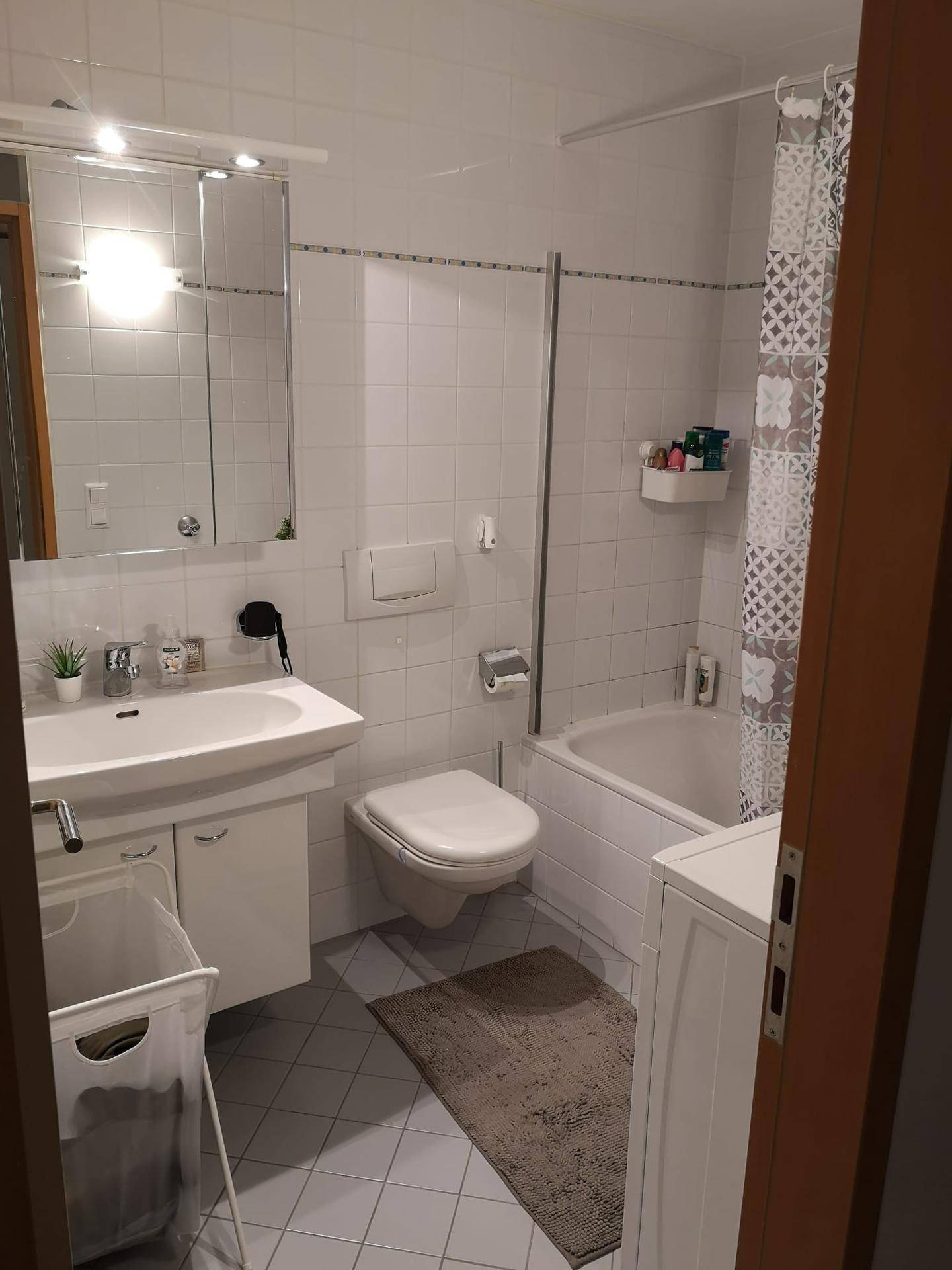 Funktionales Badezimmer mit Badewanne, Dusche, WC und Waschbecken mit Spiegelschrank.