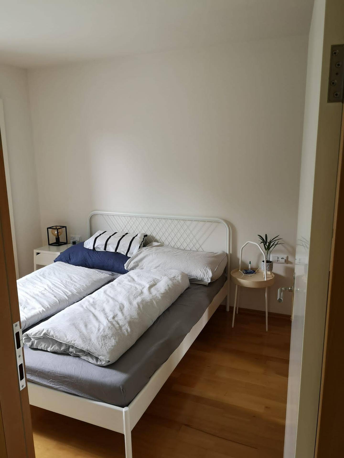 Helles Schlafzimmer mit einem Doppelbett, Nachttischen und einem warmen Holzfußboden.