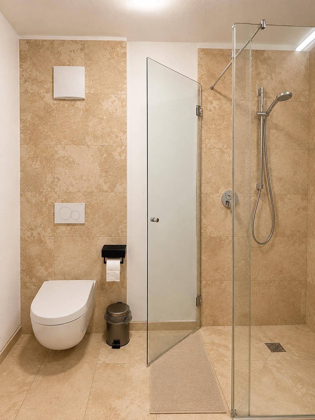 Modernes Badezimmer mit ebenerdiger Dusche und wandhängendem WC in hellen Farbtönen.