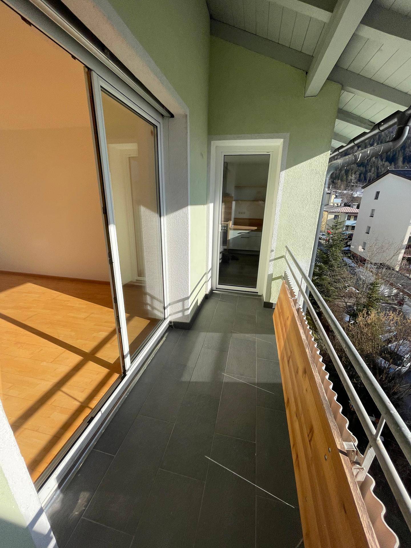 Sonniger Balkon mit Fliesenboden und Bergblick, ideal für entspannte Stunden im Freien.
