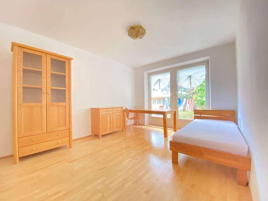 Helles Schlafzimmer mit Holzboden, weiß gestrichenen Wänden und einfacher Holzmöblierung.
