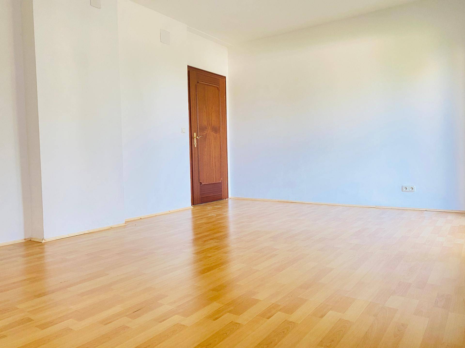 Leerer Raum mit hellem Holzboden und weiß gestrichenen Wänden, bereit zur individuellen Gestaltung.
