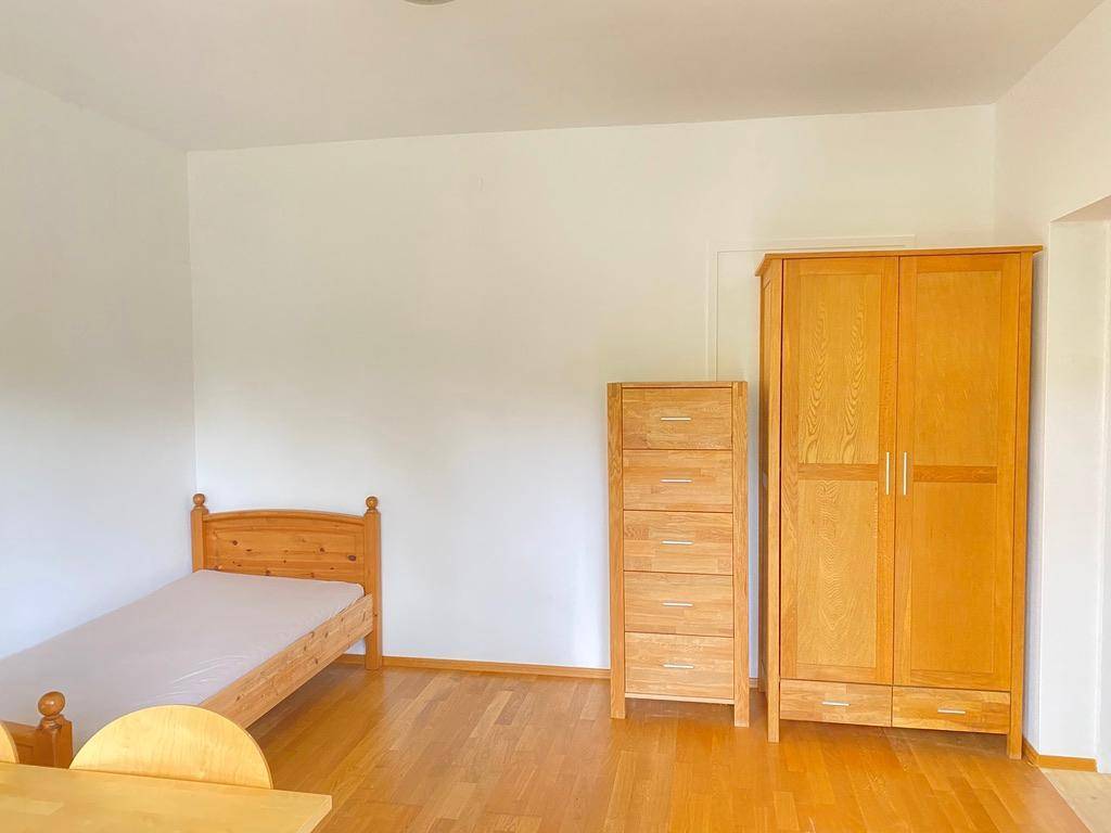 Geräumiges Schlafzimmer mit hellem Holzboden, weiß gestrichenen Wänden und passenden Holzmöbeln.