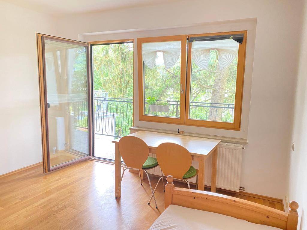 Schlafzimmer mit Zugang zu einem Balkon, ausgestattet mit einem kleinen Tisch und Stühlen.