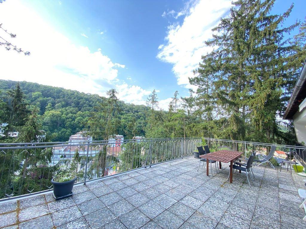 Große geflieste Terrasse mit Esstisch und Stühlen, bietet einen weiten Blick auf die grüne Landschaft.