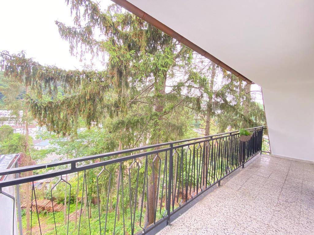 Langer Balkon mit Fliesenboden und schmiedeeisernem Geländer, bietet einen grünen Ausblick.