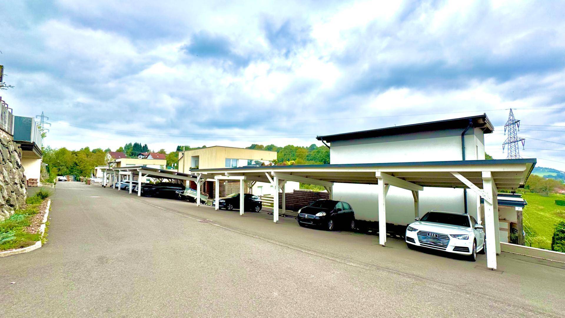 Reihe von Carports für Fahrzeuge entlang einer Zufahrtsstraße in ländlicher Umgebung.