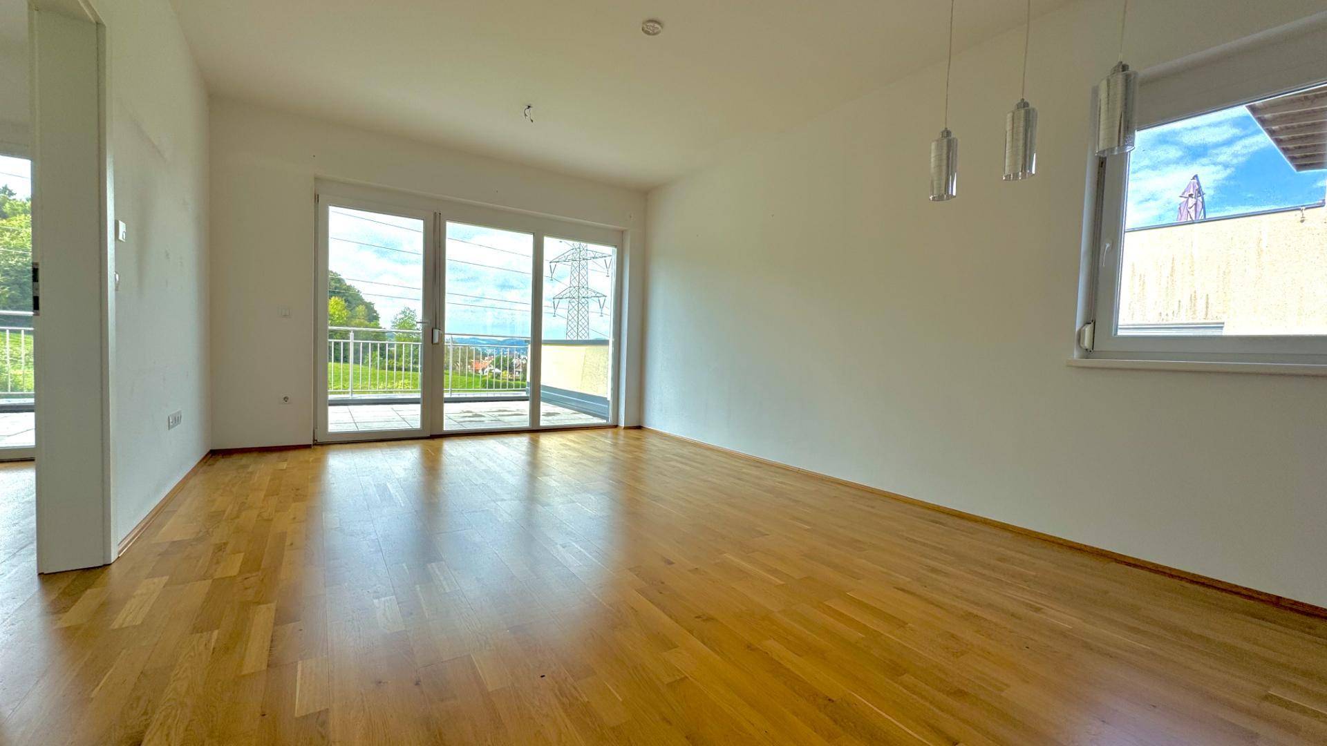 Helles Wohnzimmer mit Holzboden und weitem Blick in die grüne Landschaft.