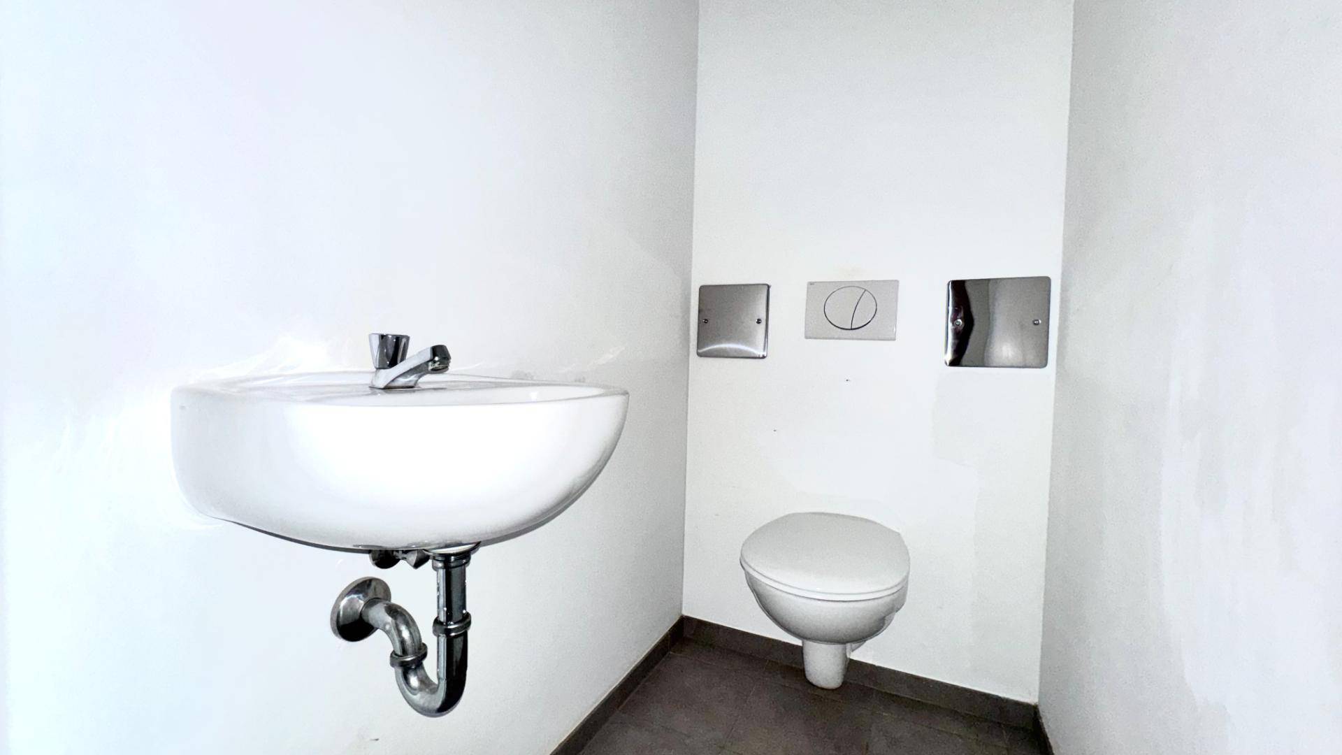 Modernes Gäste-WC mit wandhängender Toilette und kleinem Waschbecken.