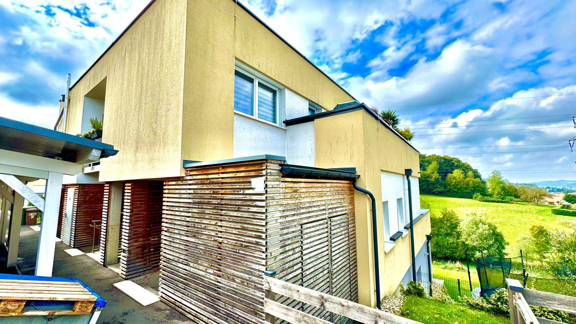 Moderne Gebäudefassade mit gelben und weißen Elementen, umgeben von Grünflächen.