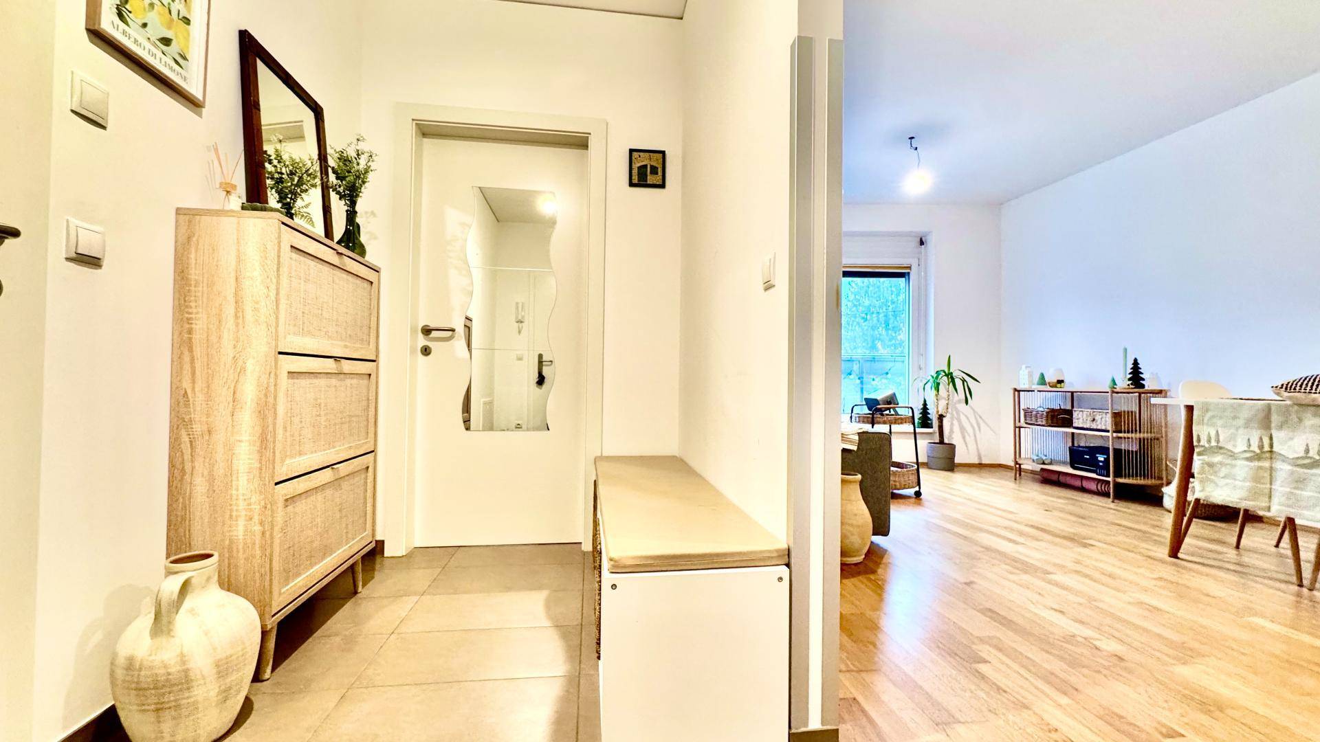 Heller Eingangsbereich mit Fliesenboden und Garderobe, der in den offenen Wohnbereich führt.